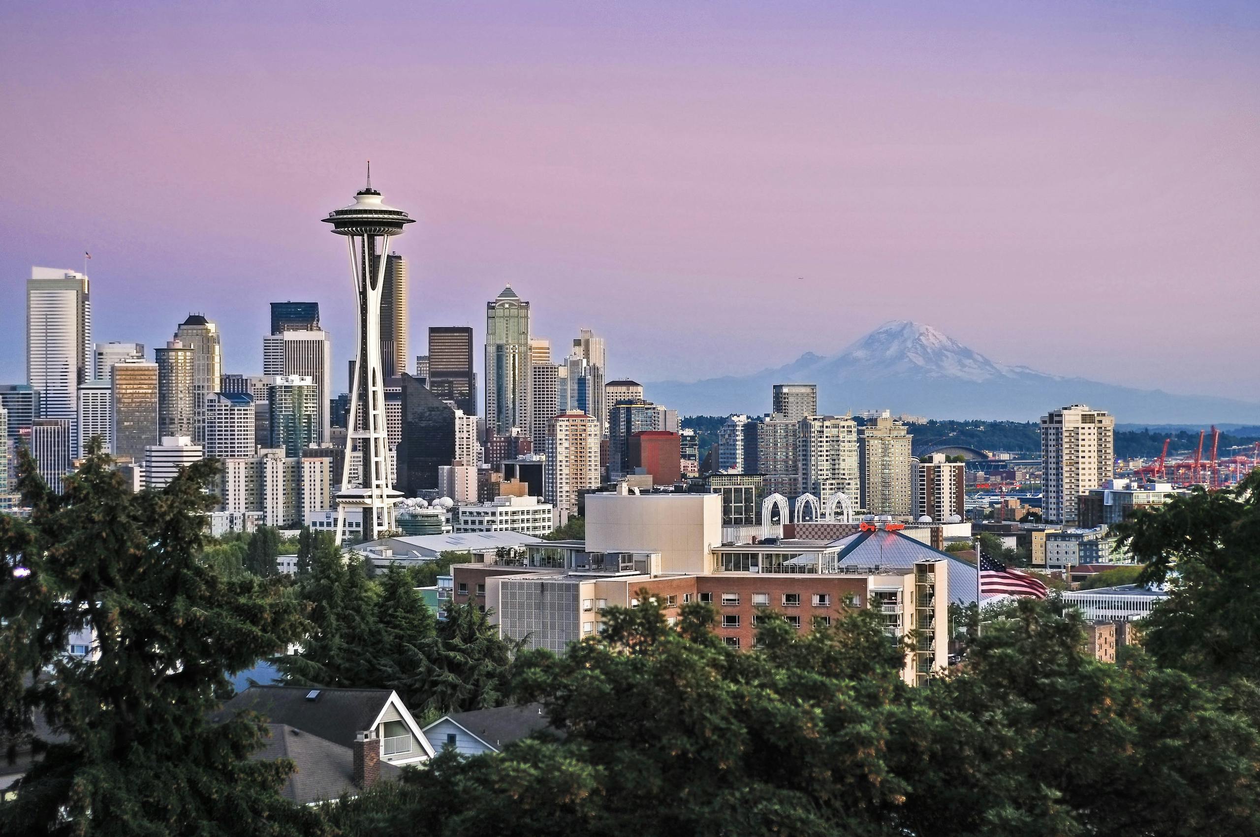 Seattle's iconic skyline featuring the Space Needle and Mount Rainier at twilight.